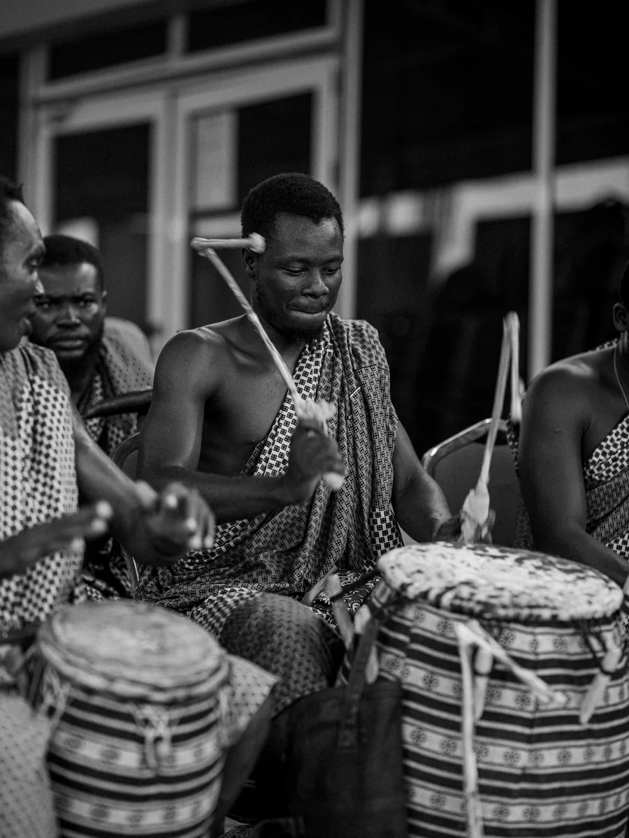 A drummer playing traditional hand drums in Accra, Ghana, black and white (representative photograph of African drumming, not the Safari Cats' own band)